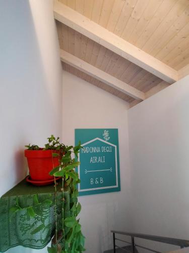 a sign in a room with a plant on a shelf at B&B Madonna degli Airali in Vezza d'Alba