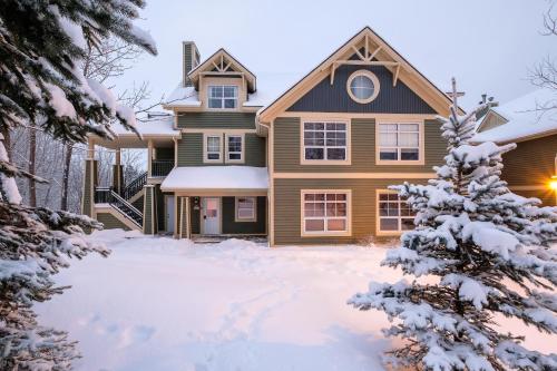 a house in the snow with a christmas tree at Tremblant Les Eaux by Rendez-Vous Mont-Tremblant in Mont-Tremblant
