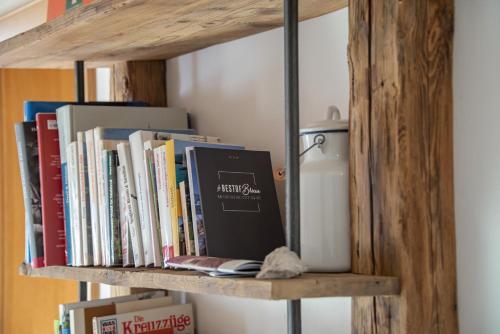 a wooden book shelf with books and a thermos at Turnerhof in Bressanone