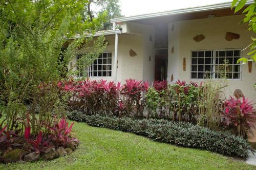 a garden in front of a house with pink flowers at Cabaña Villa Victoria in Valle de Anton