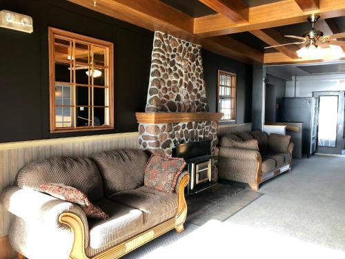 a living room with a couch and a stone fireplace at Bleu Mer, hôtel & résidences in Carleton sur Mer