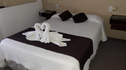 una habitación de hotel con dos cisnes blancos en una cama en Alfil Hotel en Villa Gesell