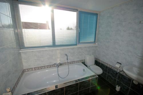 ein Badezimmer mit einer Badewanne, einem WC und einem Waschbecken in der Unterkunft Kroonstuk 2 in Nes