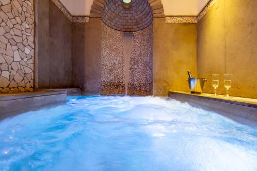 a large tub filled with blue water with wine glasses at Le Jardin Romain in Taormina