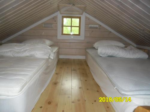 2 Betten in einem Dachzimmer mit Fenster in der Unterkunft Lussebo 9 in Lidköping