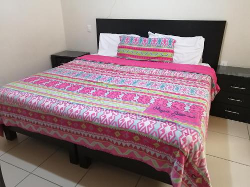 a bed with a pink comforter and two pillows at Hotel Peña Real in Bernal