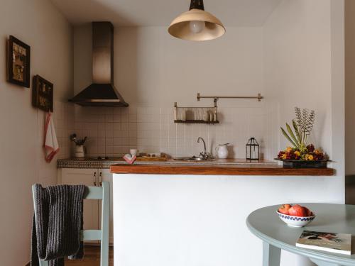 a kitchen with a counter and a table with a bowl of fruit at Hospedería del Valle Boutique Apartments in Gargantilla del Lozoya