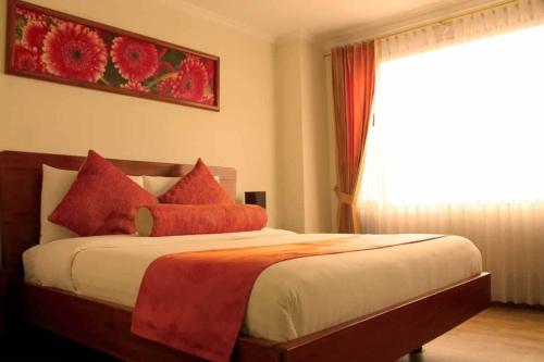 una camera da letto con un letto con cuscini rossi e una finestra di Hotel Splendor by Friends Company a Bogotá