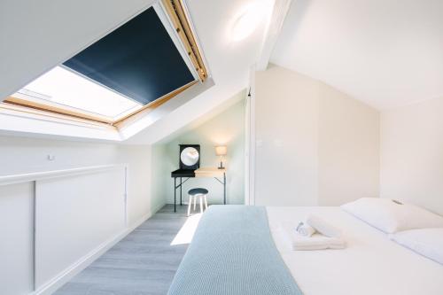 - une chambre mansardée avec un lit et une lucarne dans l'établissement Le Trendy - Duplex pétillant : Place Graslin / Dobrée, à Nantes