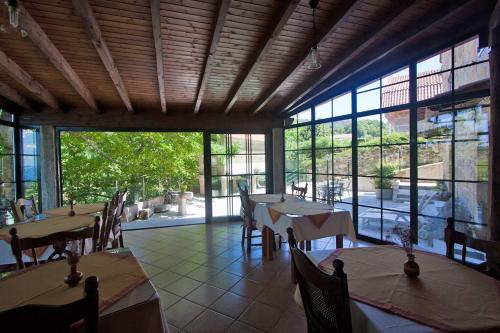 un restaurante con mesas, sillas y ventanas grandes en Casa Torre Vella, en Bueu