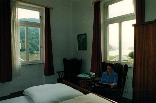 Hatzenport的住宿－Gasthaus Zur Traube，坐在窗户房间里桌子上的女人
