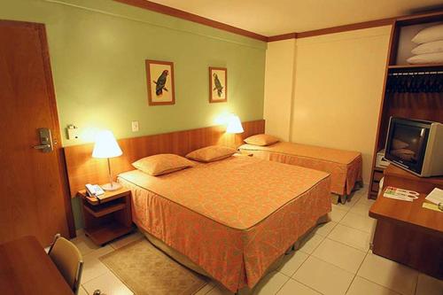 a hotel room with two beds and a television at Golden Dolphin Express in Caldas Novas