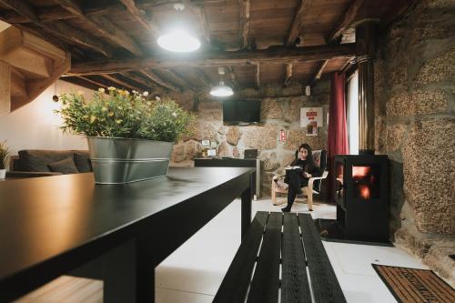 a woman sitting in a chair in a room with a fireplace at Casa Oeste in Sabugueiro