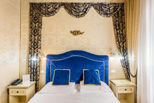 Una cama azul con dos almohadas encima. en Residenza La Campana, en Venecia