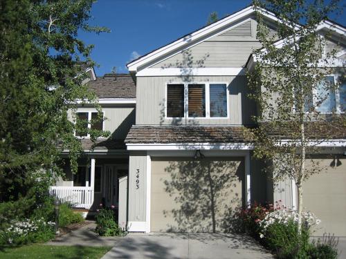 a white house with a garage at JHRL - Teton Pines Townhome #20 in Wilson