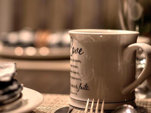 a coffee cup sitting on a table with a fork at Foster's Bethel Beach Inn in Onemo