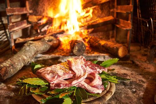 a piece of meat on a plate in front of a fire at Agriturismo Casa VolaterrA in Volterra