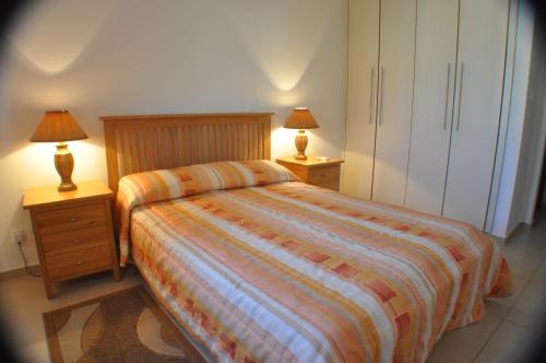 a bedroom with a bed and two night stands with lamps at 2 Bed, 2 Bath Apartment In Mandria in Mandria