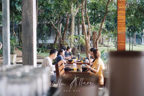 a group of people sitting at a table at a restaurant at Villa Allure Koh Mak in Ko Mak