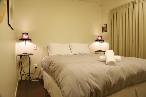 a bedroom with a large white bed with two lamps at Rocky Mountain Chalets Ohakune in Ohakune