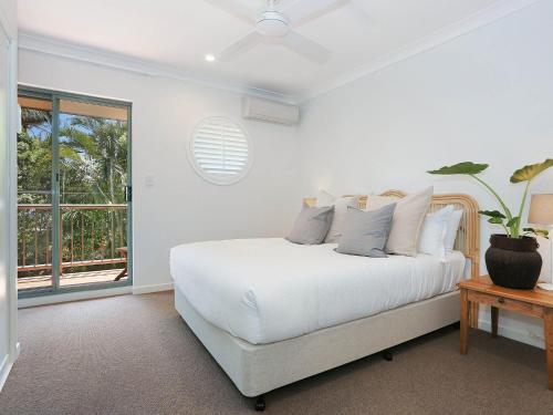 a white bedroom with a bed and a window at Byron Beachside 8 in Byron Bay