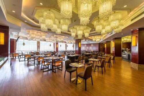 a restaurant with tables and chairs and chandeliers at 烟台静海大酒店 in Yantai