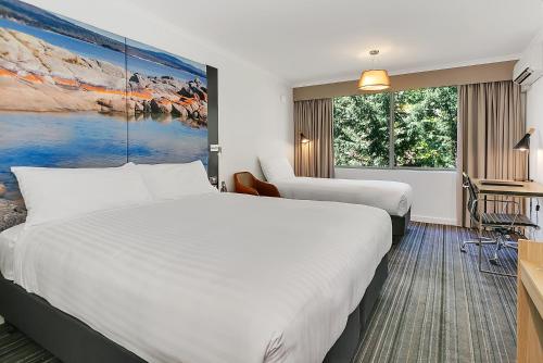 a hotel room with two beds and a large window at Mercure Launceston in Launceston