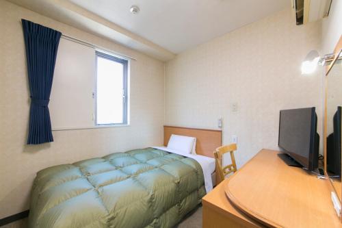 a bedroom with a bed and a desk with a computer at Hotel Econo Yokkaichi in Yokkaichi