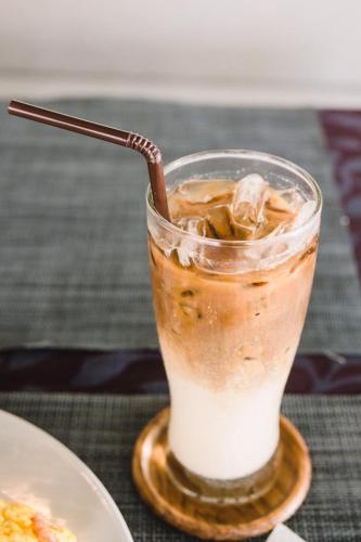 a glass of iced coffee with a spoon in it at THE BEACH CHA AM Suites in Cha Am