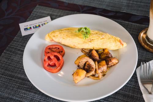 a white plate of food with a omelet and vegetables at THE BEACH CHA AM Suites in Cha Am