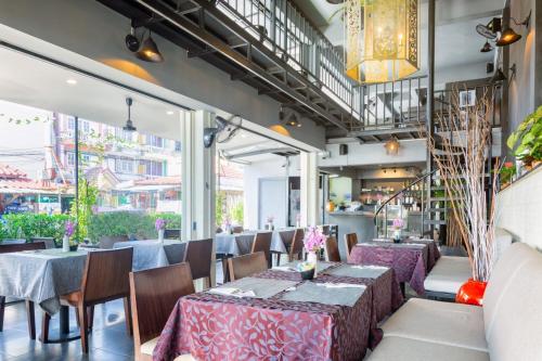 a restaurant with tables and chairs and windows at THE BEACH CHA AM Suites in Cha Am