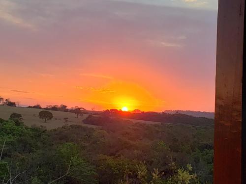 una puesta de sol en un campo con el sol en el cielo en Acqualume Cachoeiras, en Delfinópolis