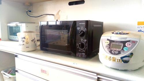 a microwave sitting on a counter next to a food processor at Little Asia Guest House in Naha