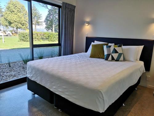 sypialnia z dużym łóżkiem i dużym oknem w obiekcie Waikanae Beach Ocean View Apartments w mieście Gisborne