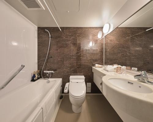 a bathroom with a toilet and a tub and a sink at HOTEL ARROWS ARASHIYAMA in Kyoto