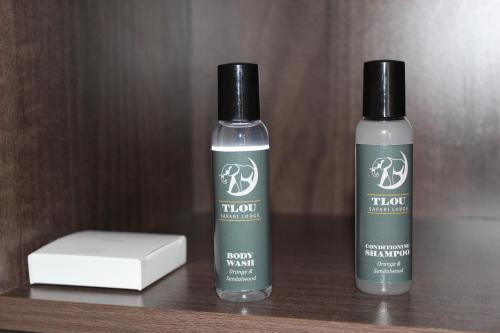 two bottles of hair products sitting on a wooden shelf at Tlou Safari Lodge in Kasane