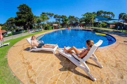 two people sitting in lawn chairs by a pool at BIG4 Moruya Heads Easts Dolphin Beach Holiday Park in Moruya