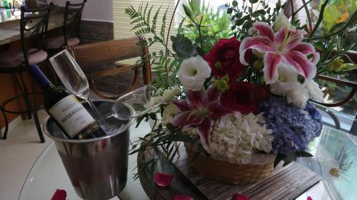 a vase of flowers and a bottle of wine on a table at Condo Bellmare in Puerto Aventuras