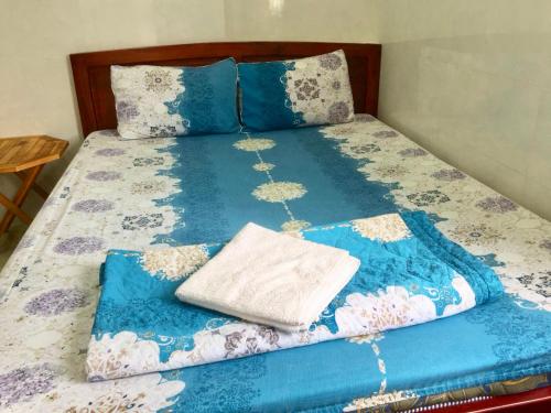 a bed with a blue and white quilt on it at Guesthouse Minh Thu in Ho Chi Minh City