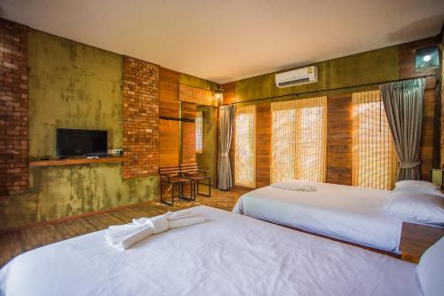 a hotel room with two beds and a television at Palm Pran Resort in Pran Buri