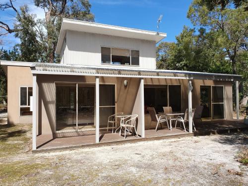 a house with a deck with a table and chairs at Waterfront Retreat At Wattle Point in Paynesville
