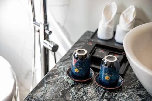 Un mostrador de baño con 2 tazas encima de un fregadero en Rosy Cruises, en Ha Long