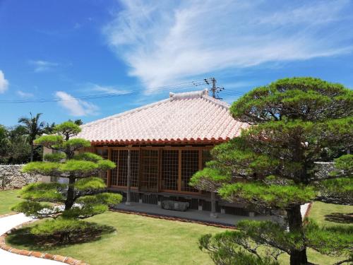 a house with a red roof and some trees at かたあきの里 in Miyako Island