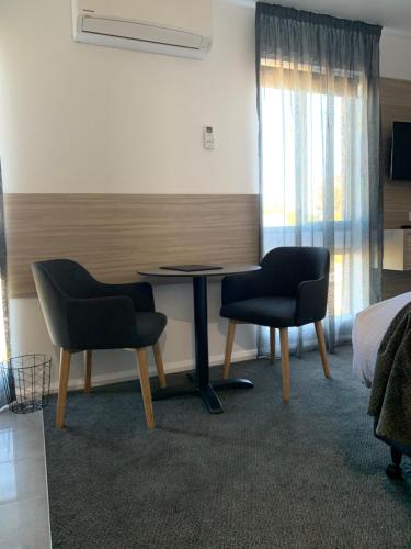 a room with two chairs and a table and a bed at Jervis Bay Motel in Huskisson