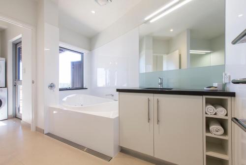 a white bathroom with a tub and a sink at Aquatic Visions in Margaret River Town