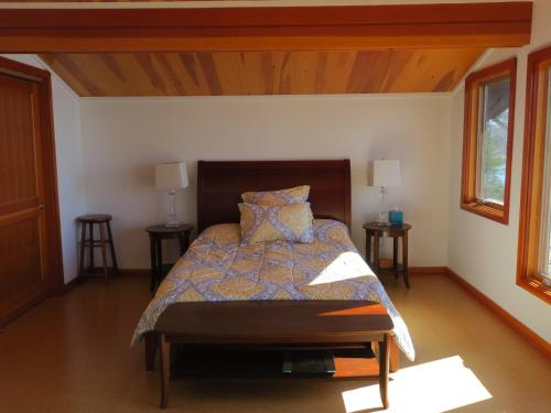 a bedroom with a bed and two tables and two windows at Acadia Ocean Front Garden Cottages in Trenton