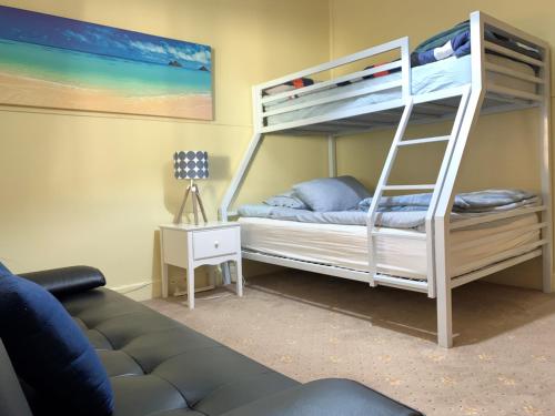 a bedroom with two bunk beds and a couch at Nautique Beach House in Rosebud