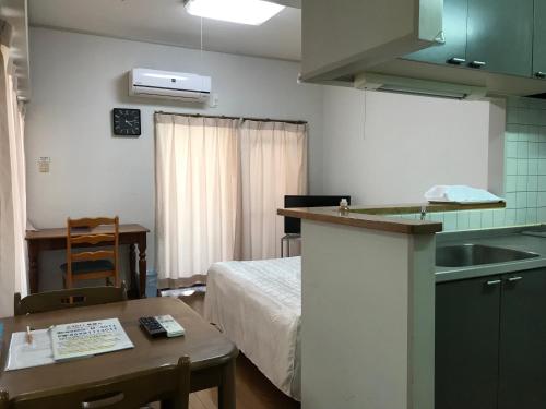 a room with a bed and a kitchen with a table at Weekly Harbourview Mansion Main Building in Naha