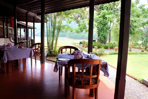 a dining room with a table and chairs on a porch at Lake Palace in Thekkady