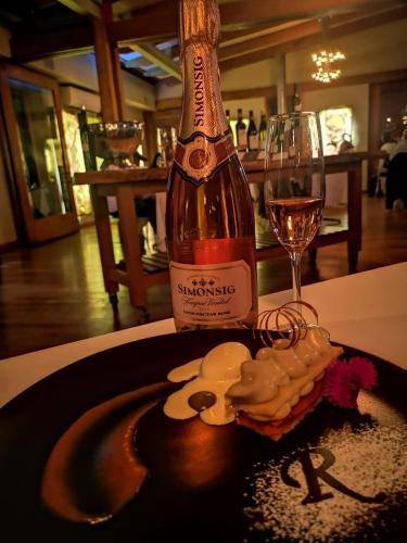 a bottle of wine and a glass on a table at Forum Homini Boutique Hotel in Krugersdorp